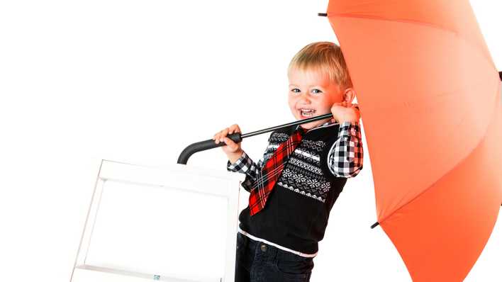 Ein Junge hält einen geöffneten Regenschirm und lacht (Quelle: Colourbox)
