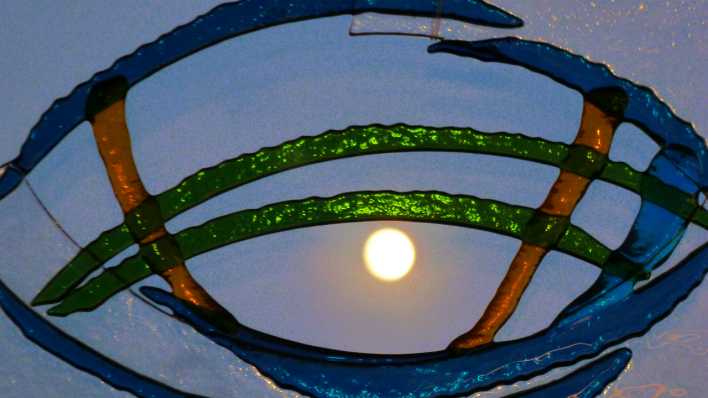 Glasmalerei mit blauen und grünen Bögen, im Hintergrund der leuchtende Mond (Quelle: rbb/OHRENBÄR/Sonja Kessen)