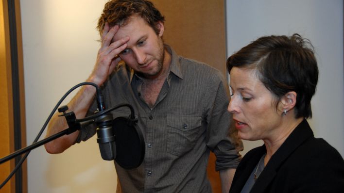 Regisseur Martin Heindel und Schauspielerin Sandra Schwittau besprechen eine Szene am Mikrofon, im Studio (Quelle: rbb/OHRENBÄR/Hanna Lippmann)