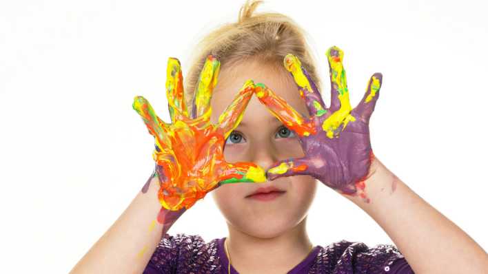 Ein Kind zeigt die von Fingerfarbe bunten Hände (Quelle: imago/McPHOTO)