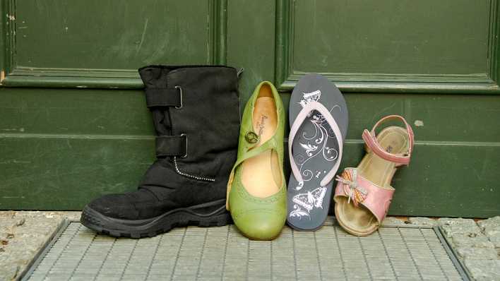 Unterschiedliche einzelne Schuhe (Stiefel, Sandale etc.) vor einer grünen Tür (Quelle: rbb/OHRENBÄR/Birgit Patzelt)