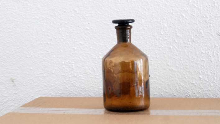 Eine braune Flasche steht verschlossen auf einem Karton (Quelle: rbb/OHRENBÄR/Birgit Patzelt)
