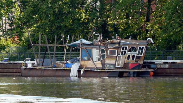 Hausboot im See, dahinter Bäume (Quelle: rbb/OHRENBÄR/Sonja Kessen)