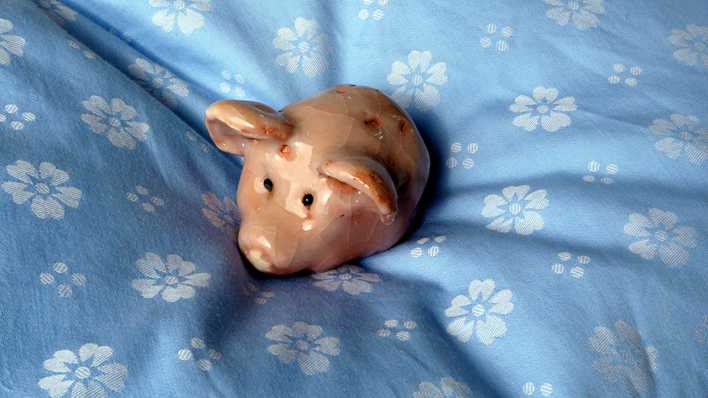 Keramikschweinchen auf einem blauen Bettbezug (Quelle: rbb/OHRENBÄR/Sonja Kessen)