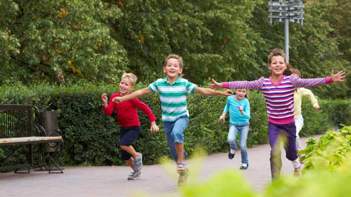 Eine Kindergruppe mit sommerlicher Kleidung, rennend auf einem Weg, im Hintergrund Bäume und Sträucher (Quelle: colourbox/Pressmaster)