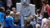 Kinder stehen vor dem großen grauen Roboter, an dem jeder drehen darf © rbb/Birgit Patzelt