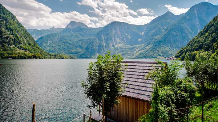 Ein Ferienhaus am See, im Hintergund sind große Berge (Quelle: Colourbox/Aleksandrs Tihonovs)