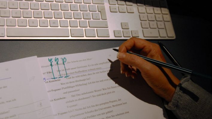 Regie-Manuskript, Hand der Regisseurin Johanna Steiner macht Notizen, darüber eine Tastatur (Quelle: rbb/OHRENBÄR/Birgit Patzelt)
