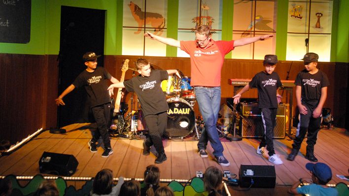Moderator Alex Schurig tanzt mit den Kids der Flying Steps Academy (Quelle: rbb/OHRENBÄR/Birgit Patzelt)