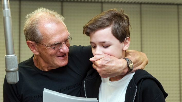 Schauspieler Joachim Kaps hält dem Sprecherkind Jeremy Kindel den Mund zu, vor dem Mikrofon (Quelle: rbb/Oliver Ziebe)