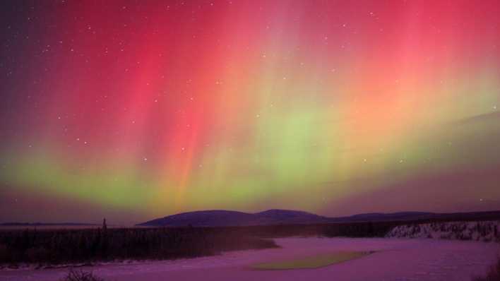 Polarlicht über einer verschneiten Landschaft (Quelle: imago images/All Canada Photos)
