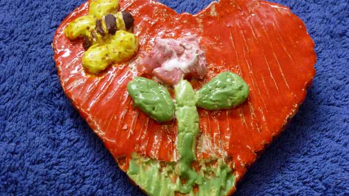 Bemalte Keramik in Herzform, bunt, Biene und Blume auf orangefarbenem Grund (Quelle: Karin Gähler)