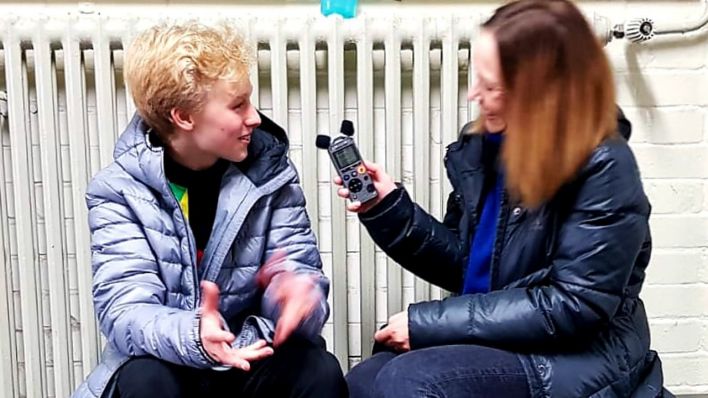 rbb 88.8-Reporterin Doreen Herbe interviewt Eiskunstlauf-Top-Talent Arthur Mai, beide sitzen vor einem Heizkörper auf einer Bank (Quelle: Detlef Mai)
