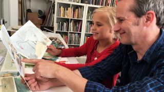 Kinder-Reporterin Lientje und Illustrator Jens Rassmus schauen gemeinsam Zeichnungen an (Quelle: rbb/OHRENBÄR/Janine Lüttemann)