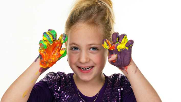 Ein Mädchen zeigt die von Fingerfarben bunten Hände wie eine Katze (Quelle: imago/McPHOTO)