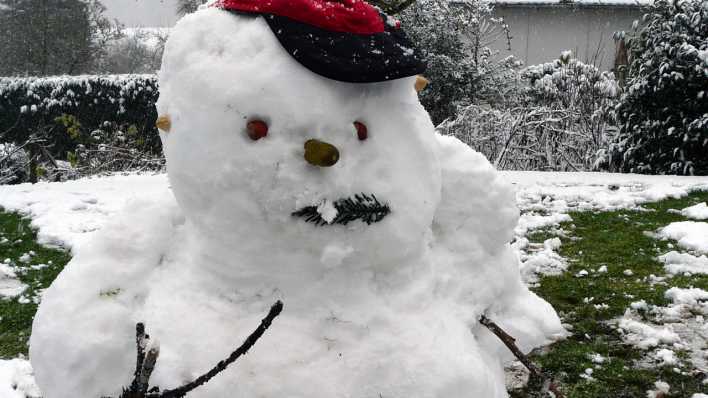 Ein Schneemann auf verschneiter Wiese, mit rot-schwarzem Basecap und Gesicht (Quelle: rbb/OHRENBÄR/Sonja Kessen)