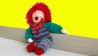 Eine Clownspuppe mit roten Haaren sitzt vor einer gelben Wand (Quelle: Karin Gähler)