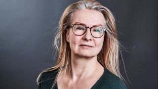 Porträt der Autorin Anne Jaspersen, mit grünem Pullover und Brille, vor dunklem Hintergrund (Quelle: Nils Jaspersen)
