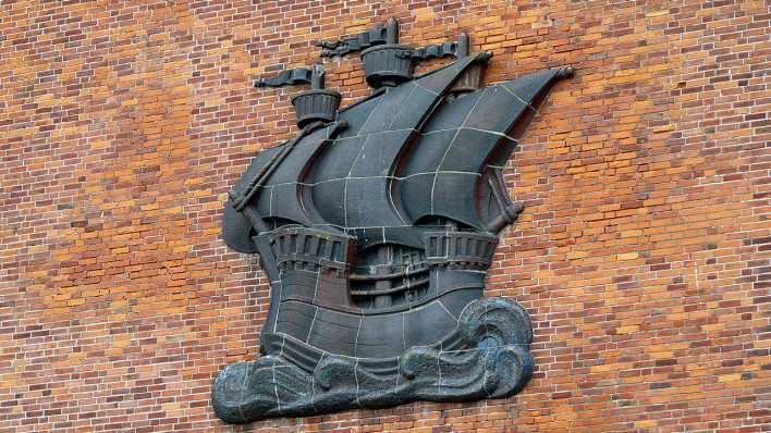 Eine Metallplakette auf einer Backsteinwand: ein Segelschiff mit drei Masten (Quelle: rbb/OHRENBÄR/Sonja Kessen)