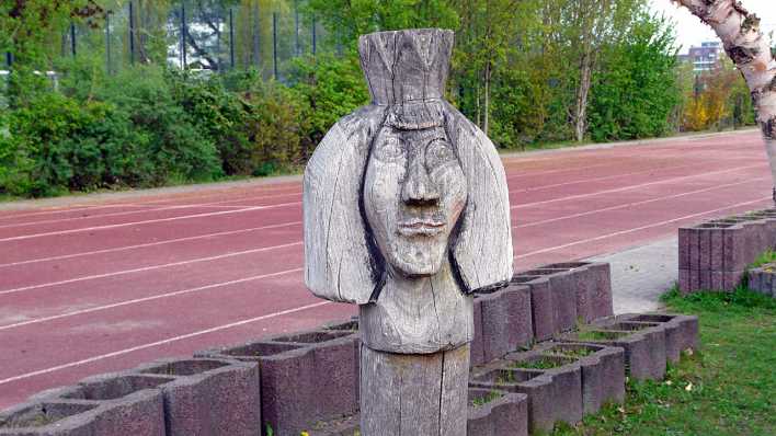 Eine Holzfigur, im Hintergrund eine rote Tartanbahn (Quelle: rbb/OHRENBÄR/Sonja Kessen)
