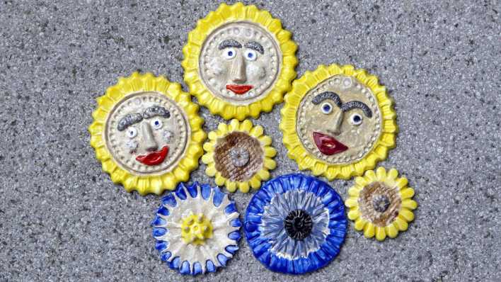 Mehrere runde Keramikfiguren, in Form von Sonnen, teilweise mit Gesichtern (Quelle: Karin Gähler)