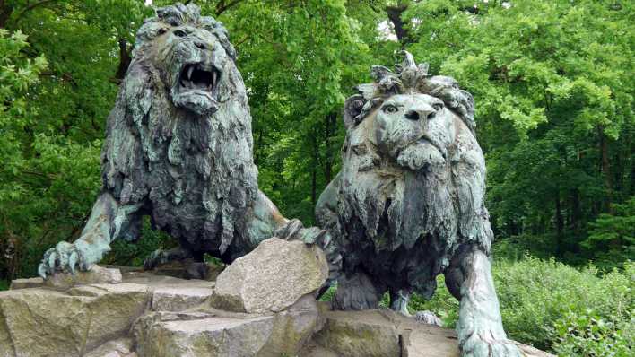 Zwei Löwen aus Stein, im Hintergrund Bäume (Quelle: rbb/OHRENBÄR/Sonja Kessen)