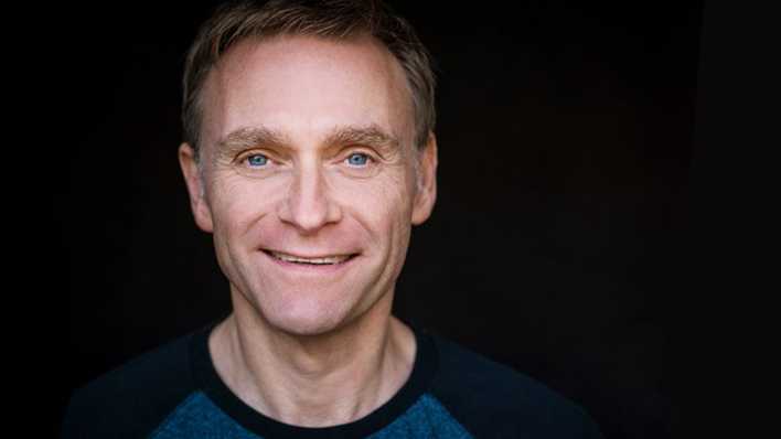 Porträt von Schauspieler Thomas Nicolai, mit blauem Shirt, schwarzer Hintergrund (Quelle: Bernd Brundert)