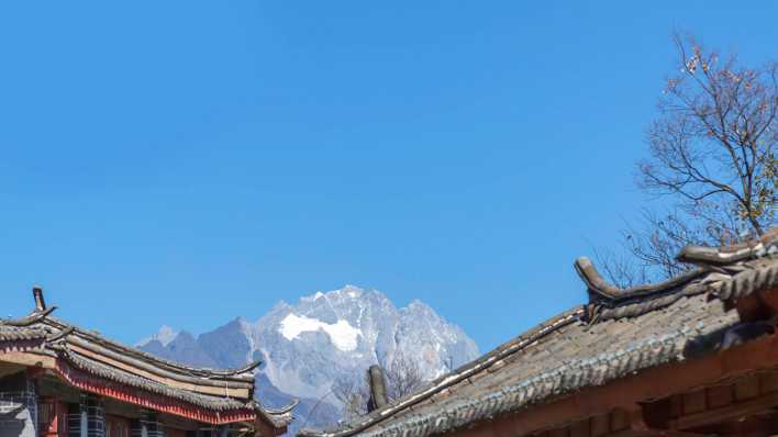 Blick auf den chinesischen Schneeberg, im Vordergrund zwei Hausdächer (Quelle: Imago/Imaginchina Tuchong)