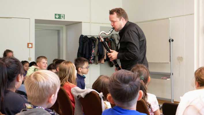 Friedemann Matzeit spielt Bass-Klarinette, vor ihm hören die Kinder im Publikum zu (Quelle: rbb/OHRENBÄR/Katharina Becker)