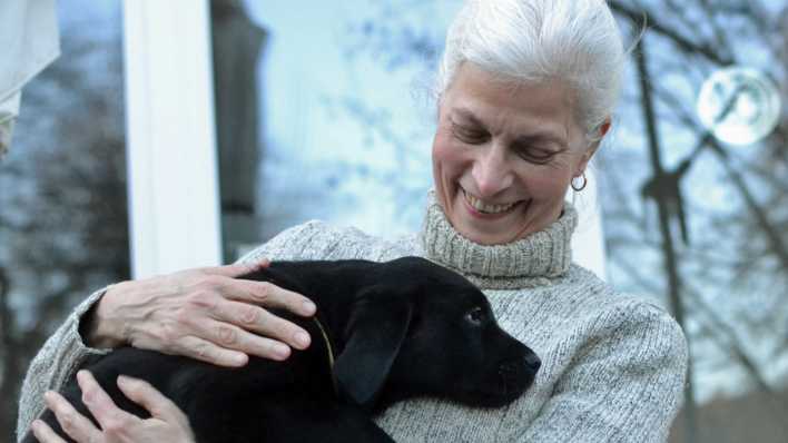 Autorin Ilke S. Prick vor einem Fenster, sie hält einen schwarzen Hundewelpen in den Händen (Quelle: privat)