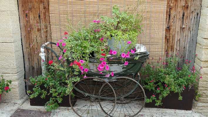 Ein alter Kinderwagen, darin sind Blumen gepflanzt (Quelle: imago/Zoonar)