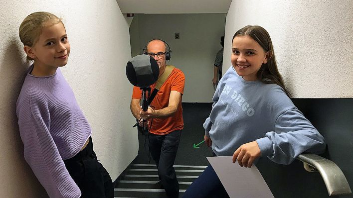 Anni Schwarz (Dimi) und Helene Herwig (Jojo) stehen auf der Treppe, Toningenieur Bernd Bechtold einige Treppenstufen darunter mit hält eine Tonangel (Quelle: rbb/OHRENBÄR/Hannah Bickhoff)