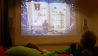 Kinder kuscheln sich in Kissen, im Hintergrund auf der Leinwand Zeichnung eines Buches "Hans im Glück" (Quelle: rbb/OHRENBÄR/Birgit Patzelt)