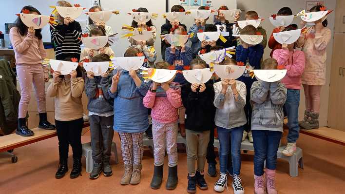 Kinder halten sich ein aus Papier gebasteltes Huhn vor das Gesicht (Quelle: Amelie Soyka)