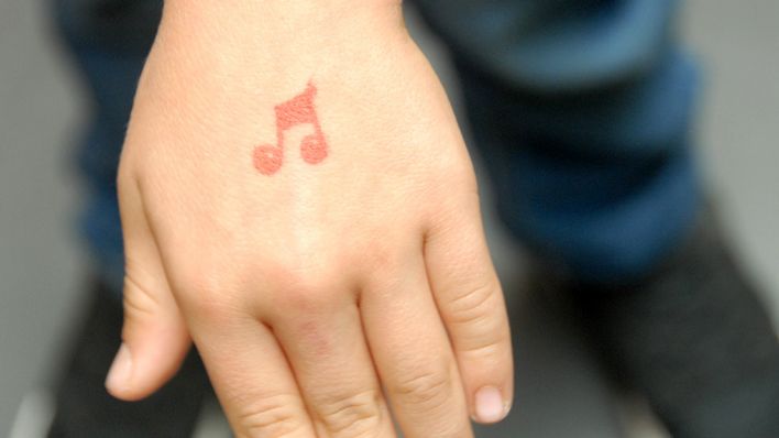 Ein Kind zeigt die linke Hand, auf dem Handrücken ist ein rote Note aufgestempelt (Quelle: rbb/OHRENBÄR/Birgit Patzelt)
