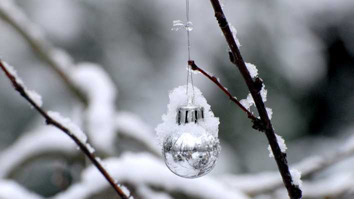 Eine verschneite Weihnachtskugel hängt an einem Ast (Quelle: rbb/OHRENBÄR/Birgit Patzelt)