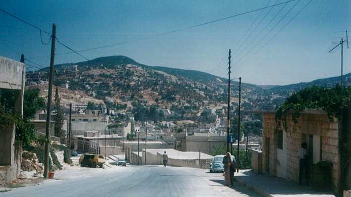 Foto einer jordanischen Stadt, im Hintergrund ein bebauter Berg (Quelle: Burtchen Bataineh)