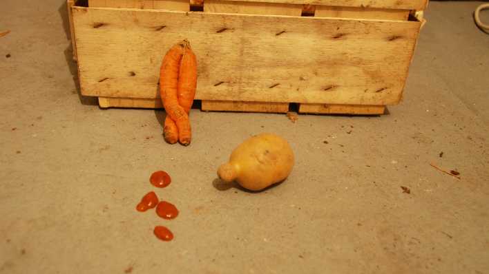 Eine Holzkiste, davor eine Mohrrübe, eine Kartoffel und Ketchupkleckse (Quelle: rbb/OHRENBÄR/Birgit Patzelt)