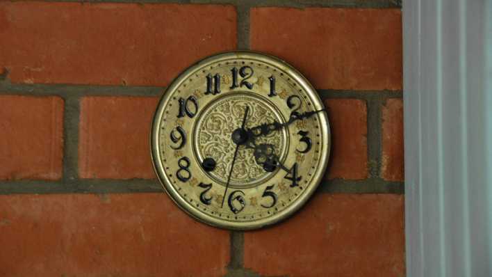 Eine messingfarbene Uhr an einer Backsteinwand, innen (Quelle: rbb/OHRENBÄR/Birgit Patzelt)