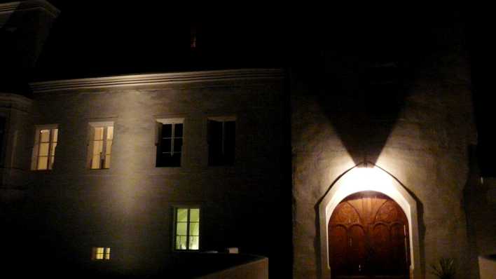 Ein kleines Schloss bei Nacht, es ist an Tür und Fenstern beleuchtet (Quelle: rbb/OHRENBÄR/Sonja Kessen)