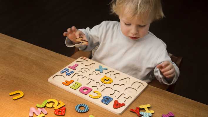 Kleines Kind steckt bunte Buchstaben in eine Buchstabenschablone (Quelle: imago/Bernhard Classen)