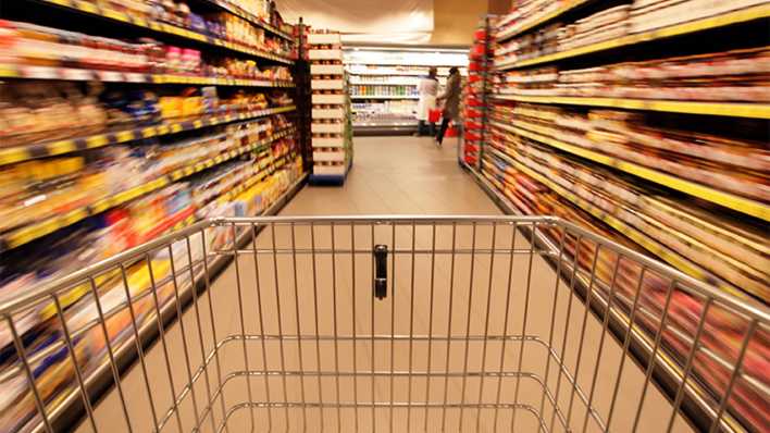 Ein Einkaufswagen zwischen zwei Regalen im Supermarkt (Quelle: imago/wolterfoto)