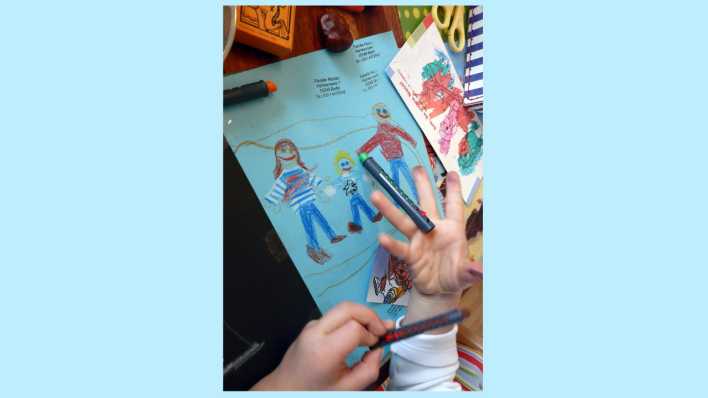 Blick über die Schulter eines Kindes, eine bemalte Hand und dahinter eine Zeichnung (Quelle: rbb/OHRENBÄR/Sonja Kessen)