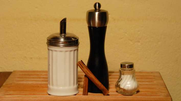Zuckerdose, Pfeffermühle, Zimtstangen und Salzstreuer auf einem kleinen Holztisch (Quelle: rbb/OHRENBÄR/Birgit Patzelt)