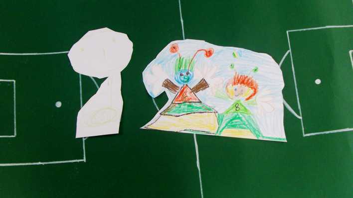 Ausgeschnittene Zeichnungen auf einem grünen Fußballfeld aus Papier (Quelle: rbb/OHRENBÄR)
