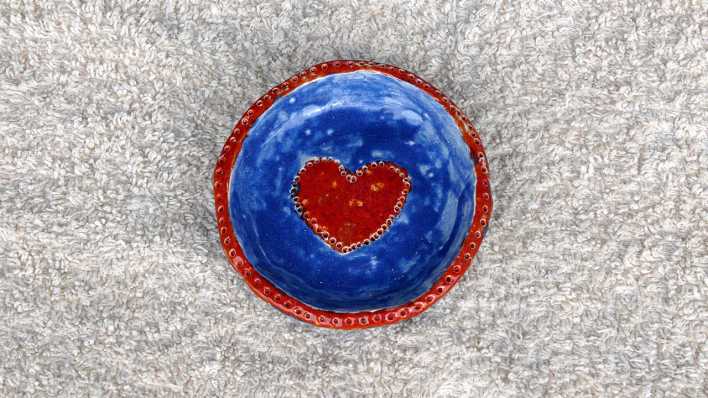Eine blau-rote Tonbastelei, rotes Herz in der Mitte, auf einem hellen Teppich (Quelle: Karin Gähler)
