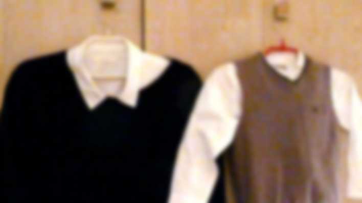 Verschwommenes Bild: zwei Kleiderbügel mit jeweils Hemd und Pullover, einmal für einen Erwachsenen und einmal für ein Kind (Quelle: rbb/OHRENBÄR/Sonja Kessen)