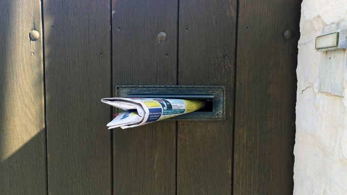 Hoftür aus Holz (Ausschnitt), im Zeitungsschlitz steckt eine Zeitung, rechts ist eine Klingel (Quelle: rbb/OHRENBÄR/Birgit Patzelt)