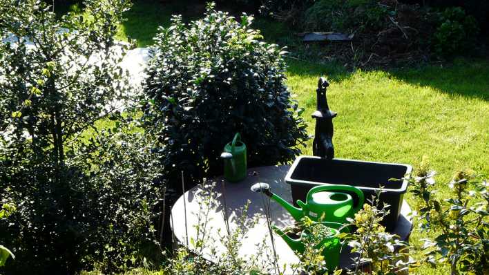 Garten mit Handpumpe, Gießkanne, kleinen Bäumen und einer grünen Wiese (Quelle: rbb/OHRENBÄR/Sonja Kessen)