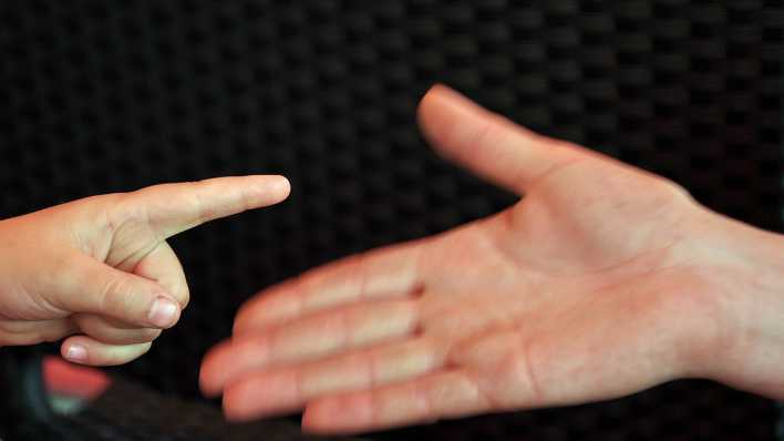 Der Zeigefinger einer kleinen Hand zeigt auf eine geöffnete große Frauenhand (Quelle: imago images/Steinach)